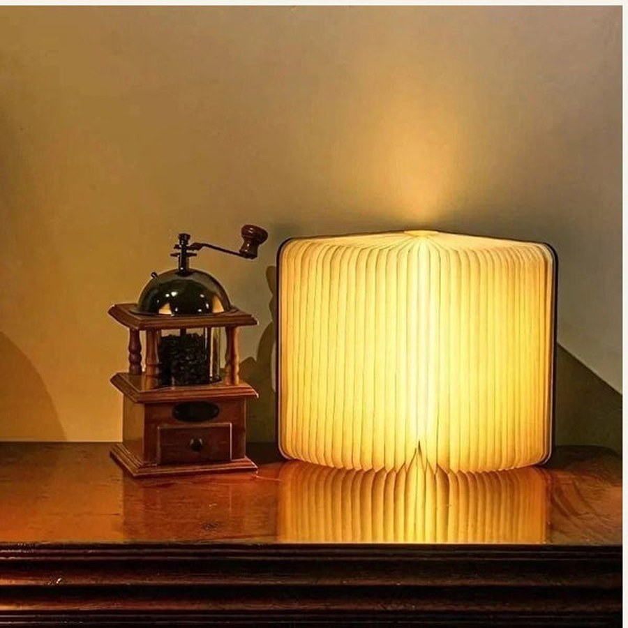 Folding book lamp glowing on a wooden table