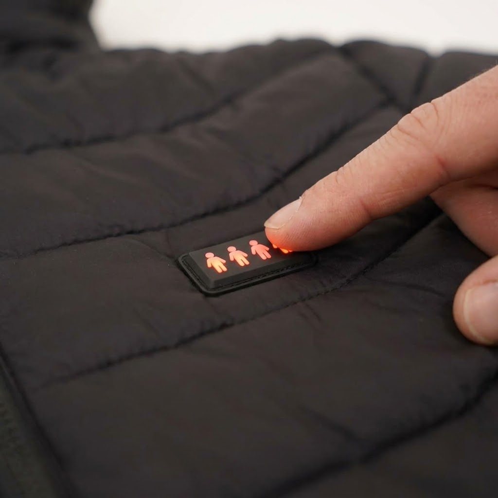 Finger pressing the lit heat control button on the jacket chest