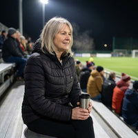Woman staying warm on the bleachers at a night game in the heated jacket